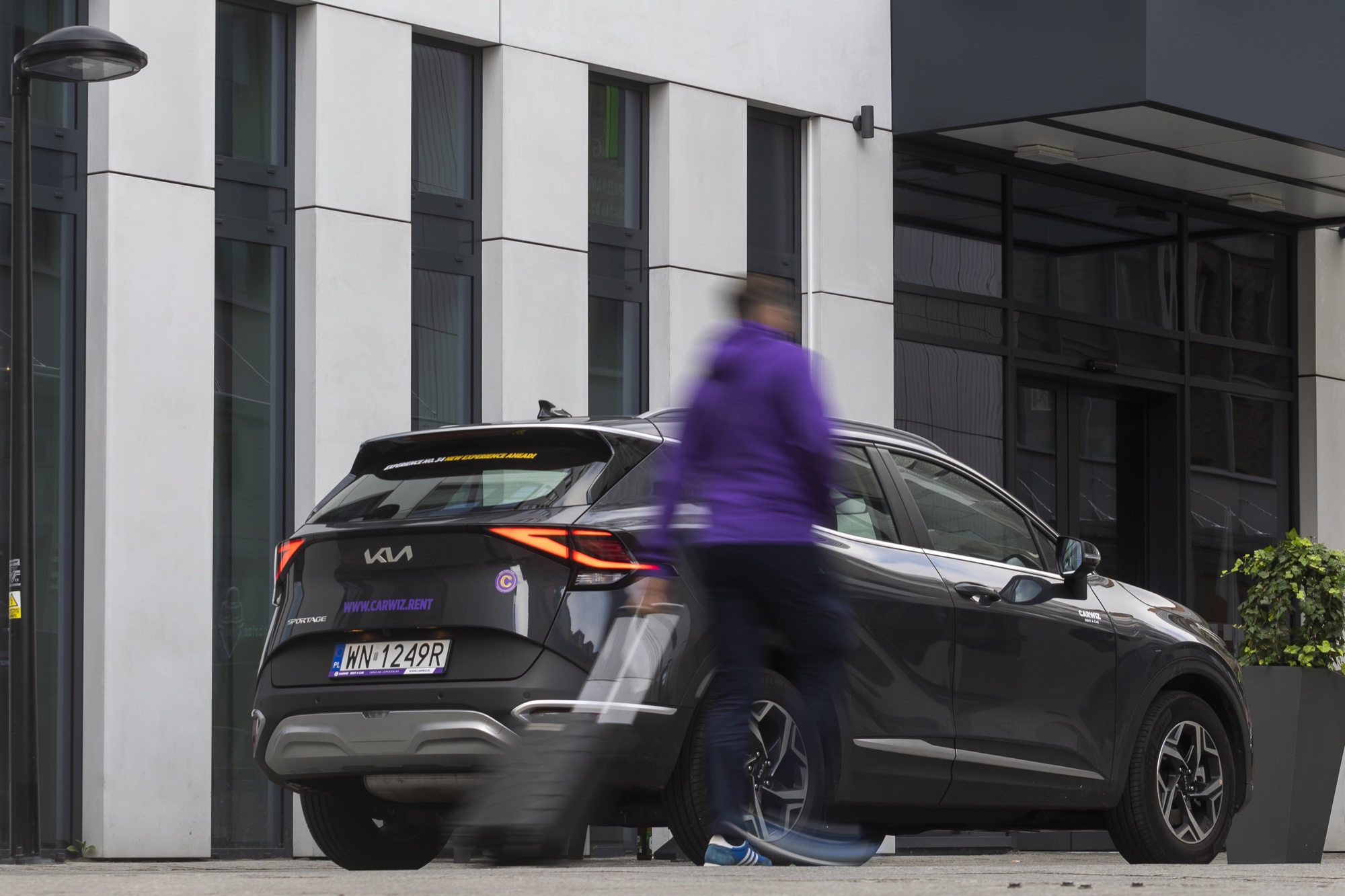 Carwiz Kia Sportage pod hotelem, klient w fioletowej bluzie